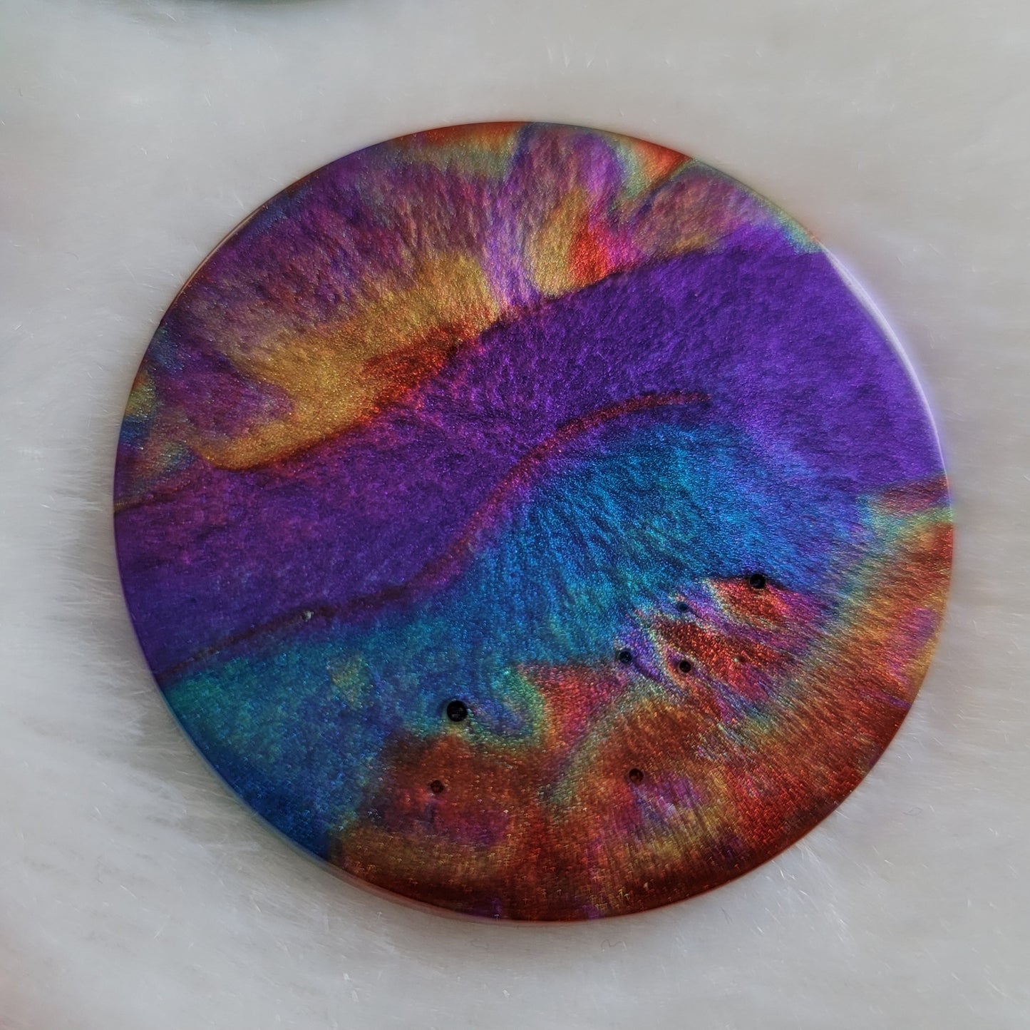 Round epoxy resin piece with colorful shimmering psychedelic swirls.