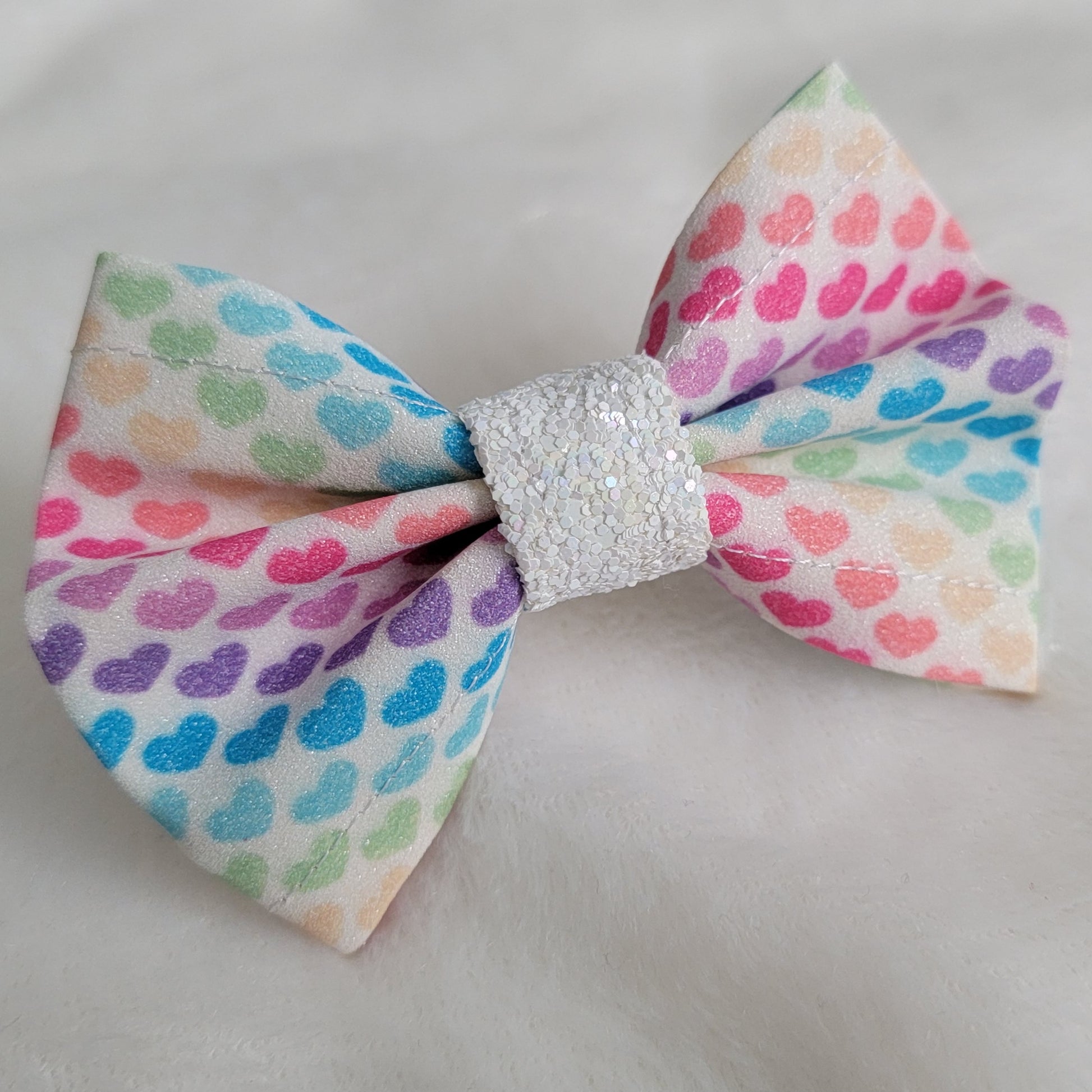 Small glitter bow with diagonal stripe rainbow hearts.