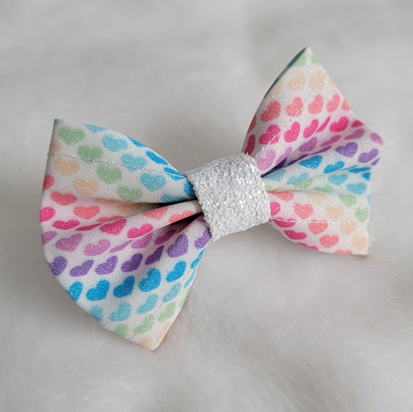 Small glitter bow with diagonal stripe rainbow hearts.