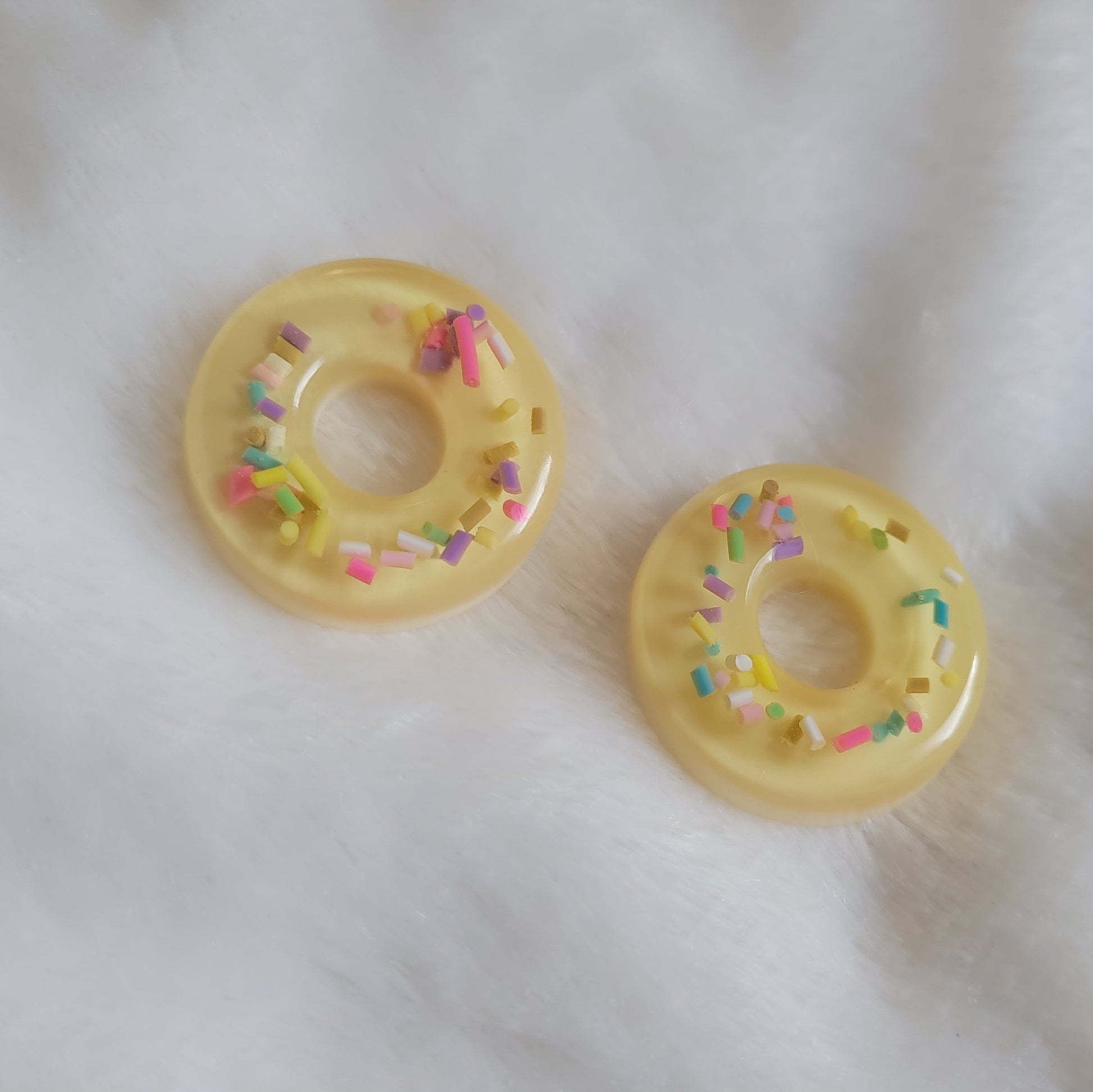 Off-white donut shaped epoxy resin pieces with rainbow sprinkles.