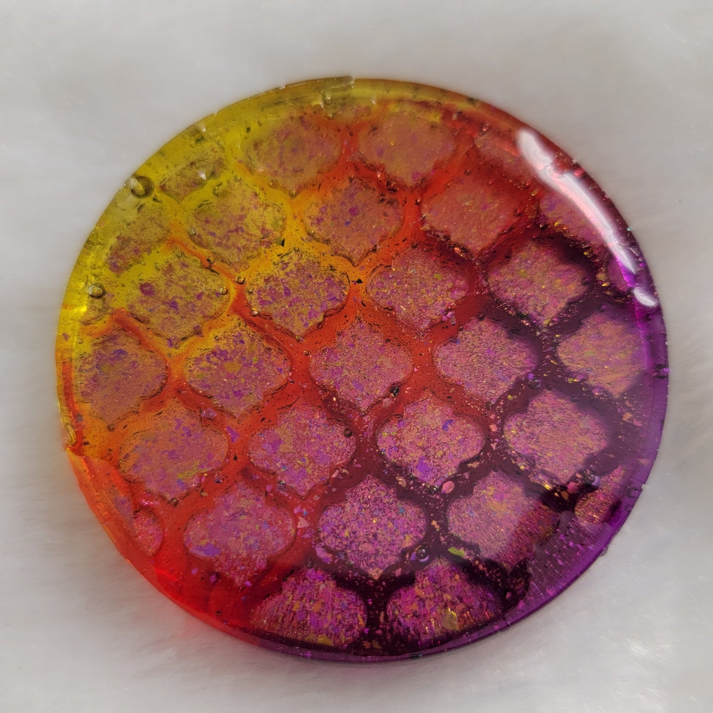 Round epoxy resin piece with geometric tile pattern, pink/gold iridescent pigment and translucent yellow, red and purple base.