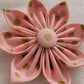 Fabric flower made with pastel peach-pink cotton with gold dots.