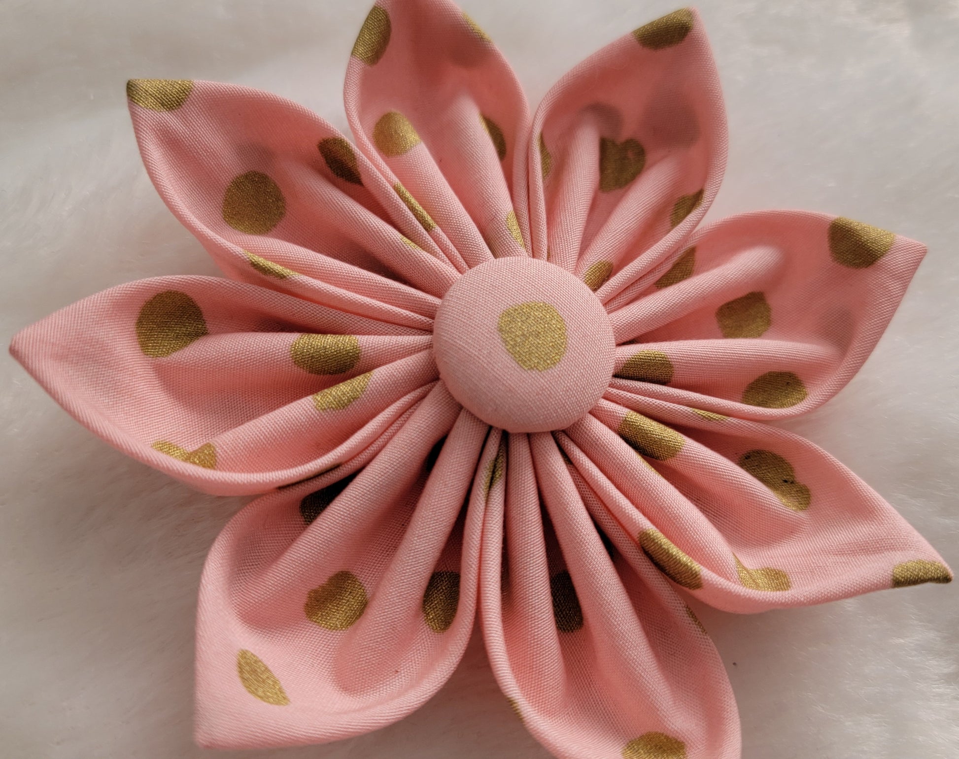 Fabric flower made with pastel peach-pink cotton with gold dots.