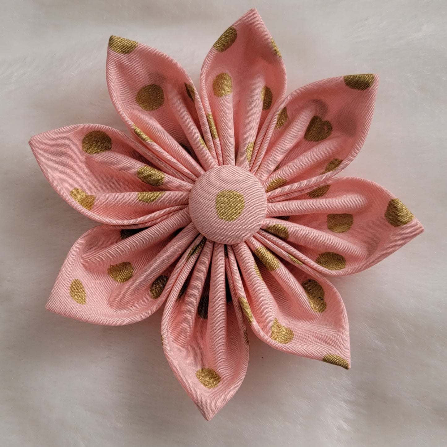 Fabric flower made with pastel peach-pink cotton with gold dots.