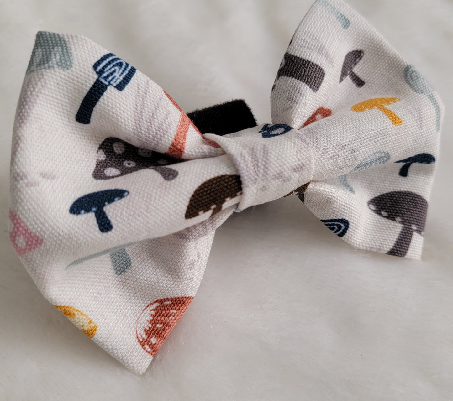 Fabric pet bowtie, natural white cotton canvas with multicolor mushrooms print in muted earthy colors.