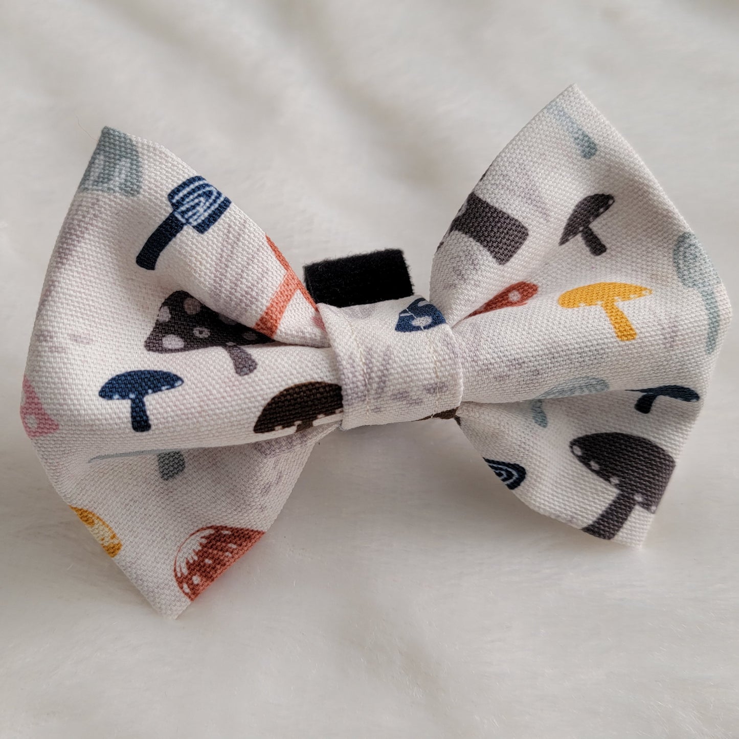 Fabric pet bowtie, natural white cotton canvas with multicolor mushrooms print in muted earthy colors.