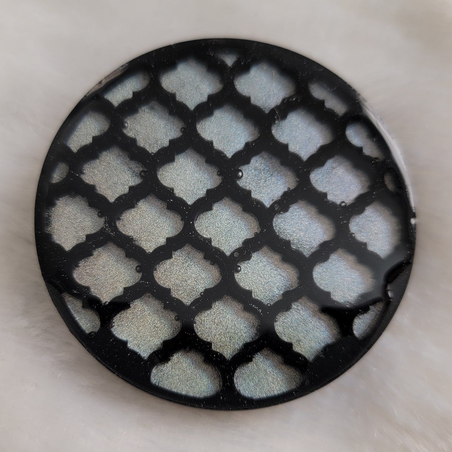 Round epoxy resin piece with black and iridescent silver lattice pattern.