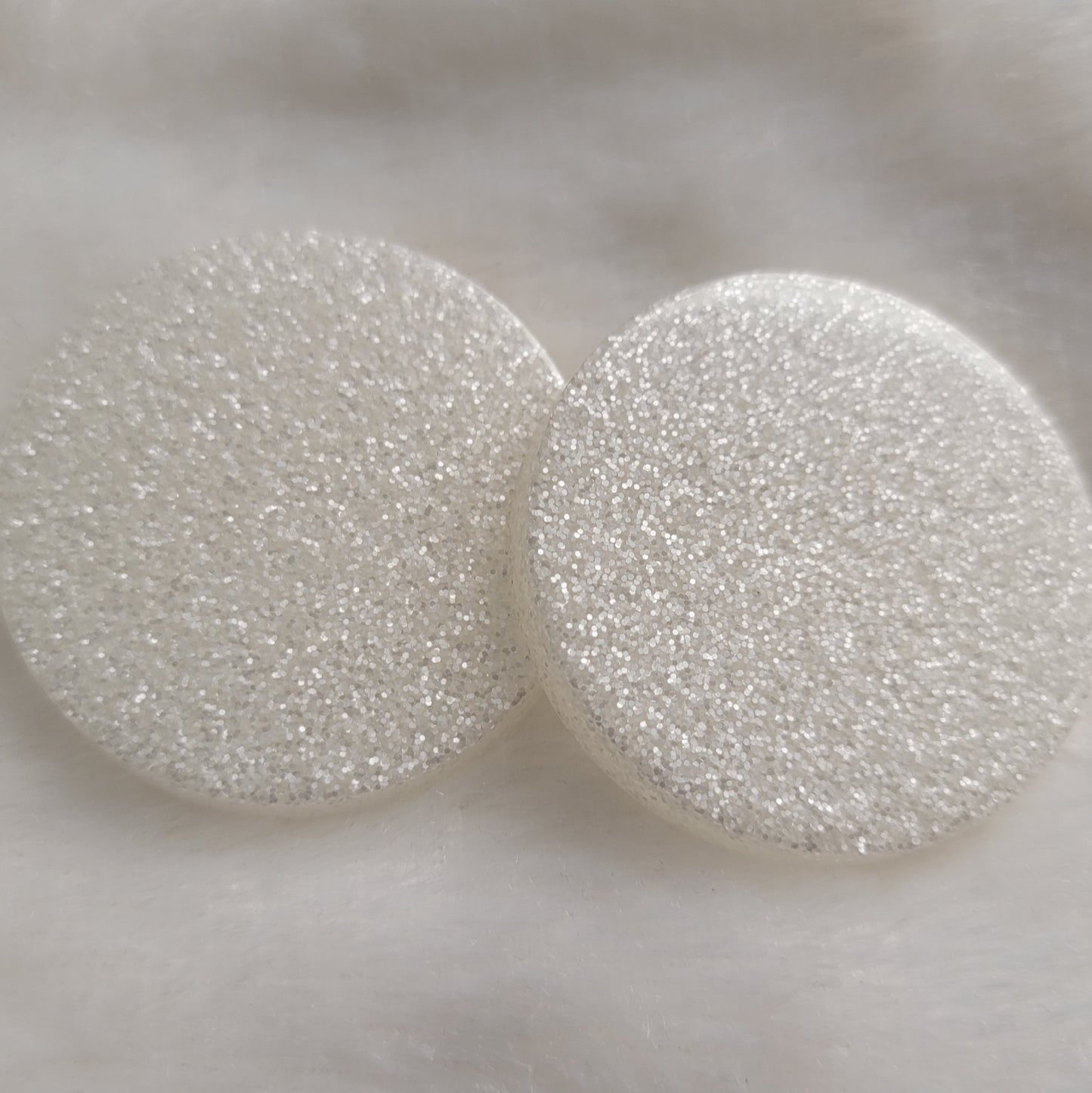 Two round epoxy resin pieces with satin white glitter.