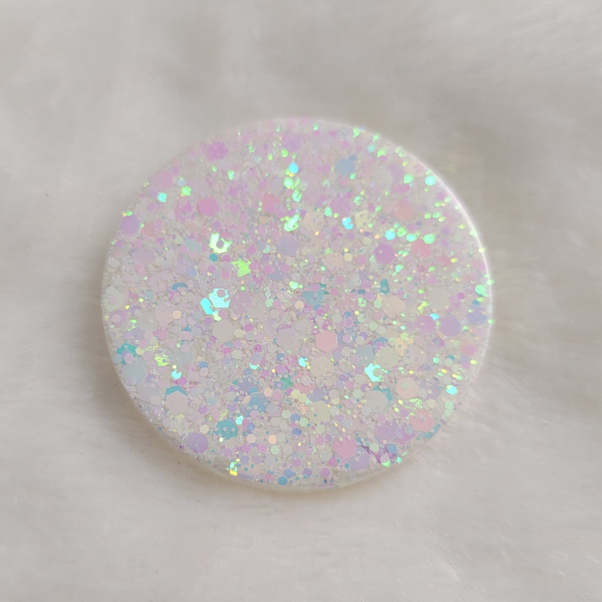 One round epoxy resin piece with iridescent white glitter.