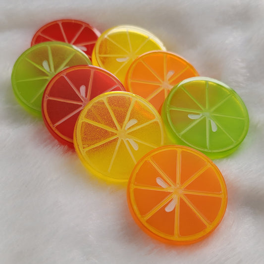 Eight round epoxy resin pieces in vibrant translucent colors with painted details to look like citrus slices.