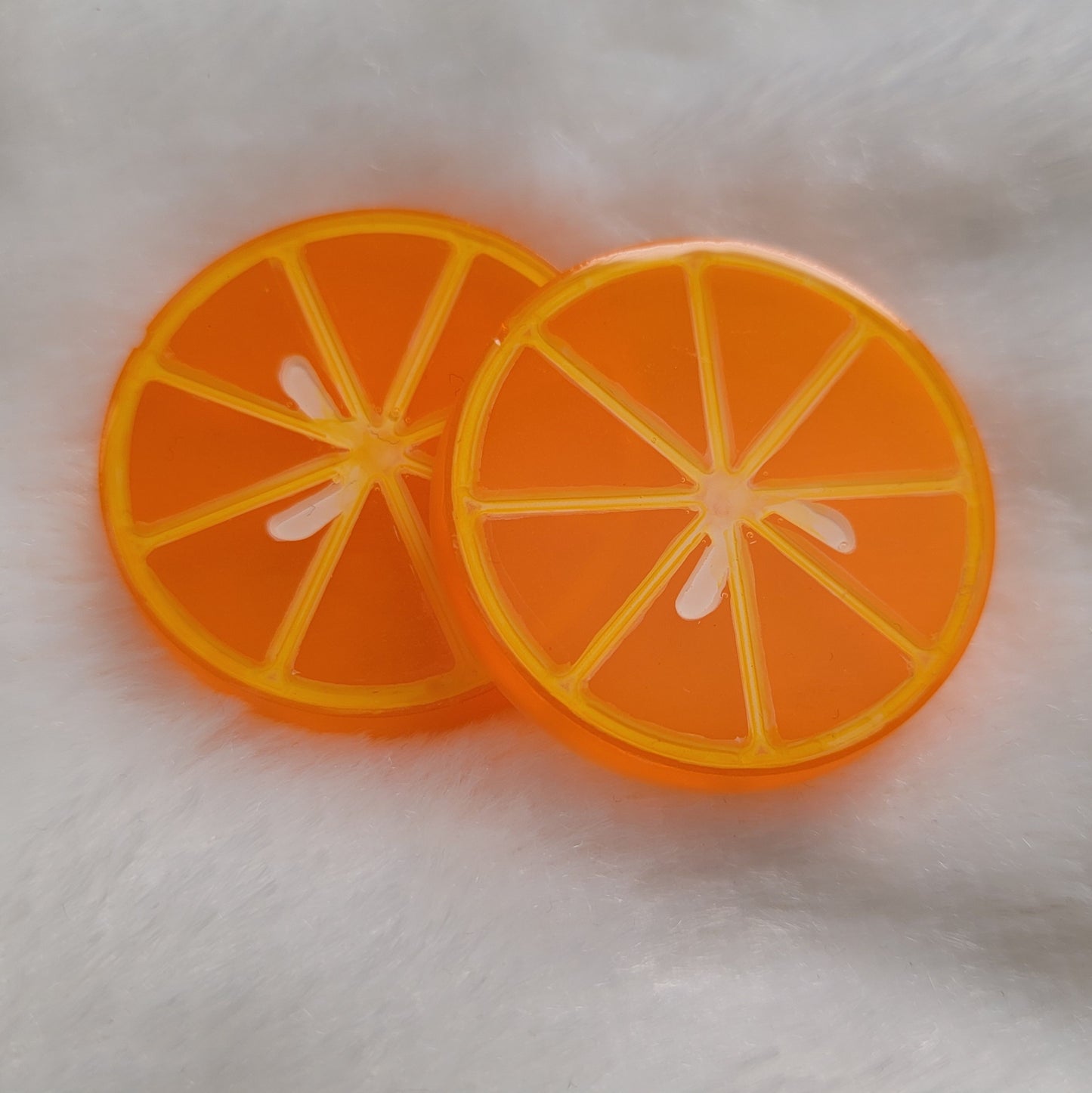 Two round epoxy resin pieces, bright orange translucent color with details to look like orange slice.