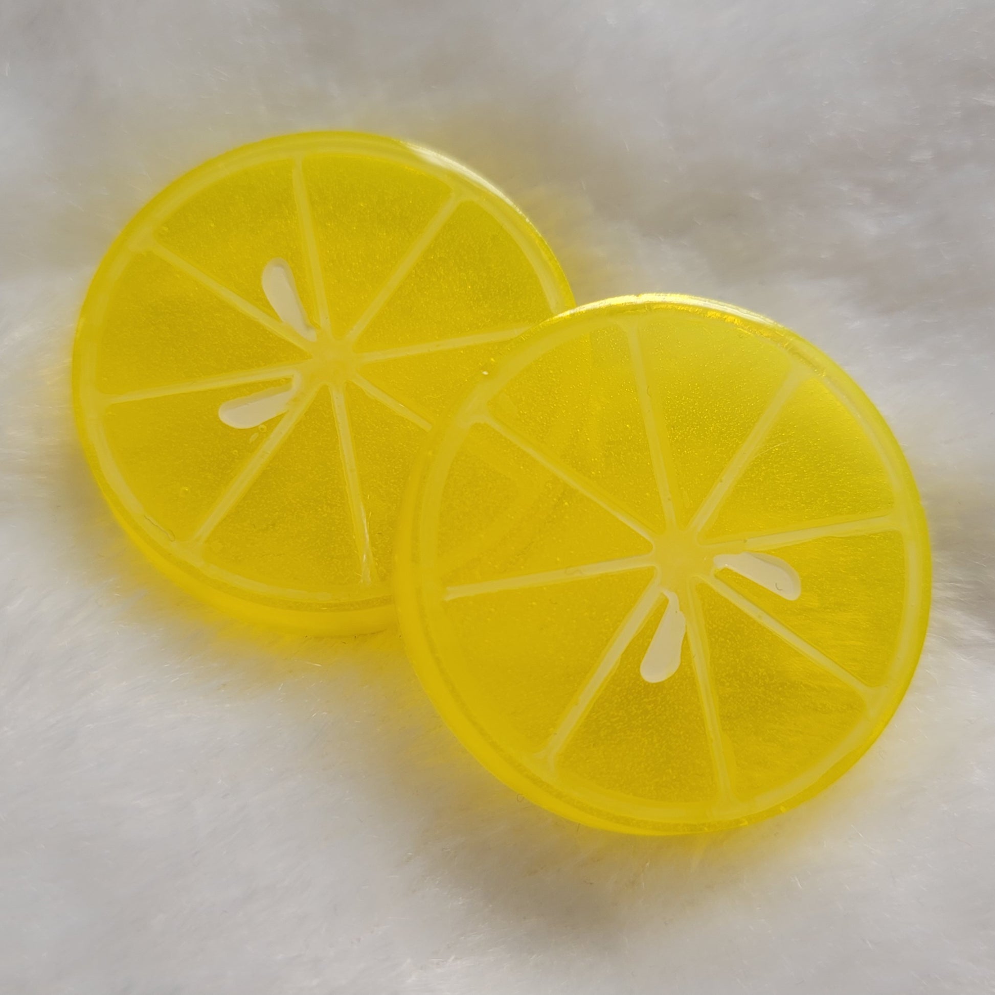 Two round epoxy resin pieces, bright yellow translucent color with details to look like lemon slice.