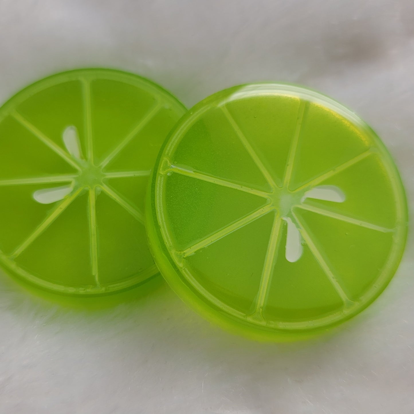 Two round epoxy resin pieces, bright green translucent color with details to look like lime slice.