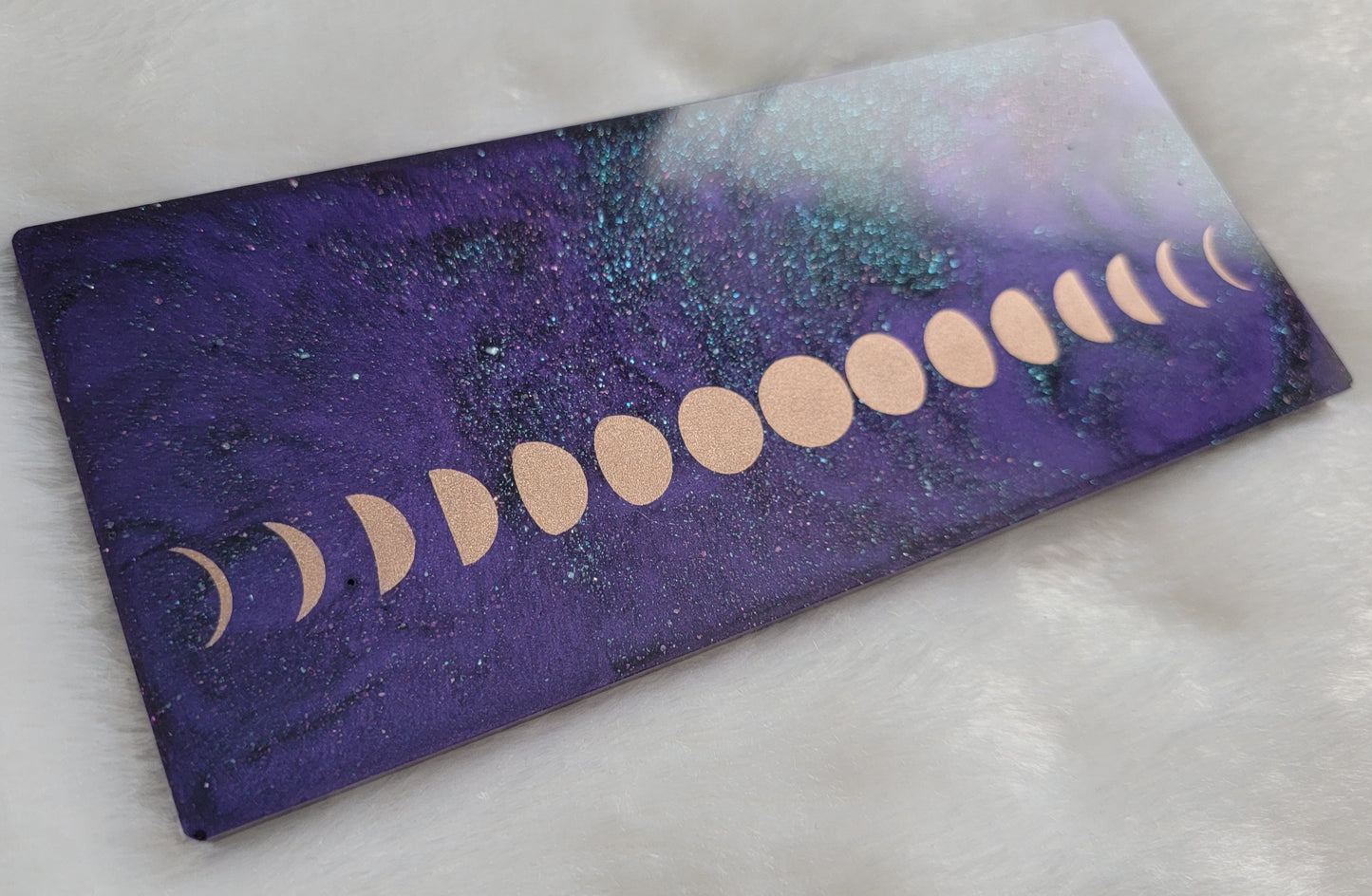 Rectangular epoxy resin piece with metallic moon phases motif on deep purple and iridescent green sparkle base.