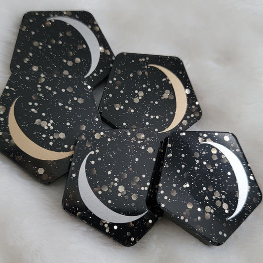 Five pentagon shaped epoxy resin pieces, black with silver glitter bases with silver and gold crescent moon motif.