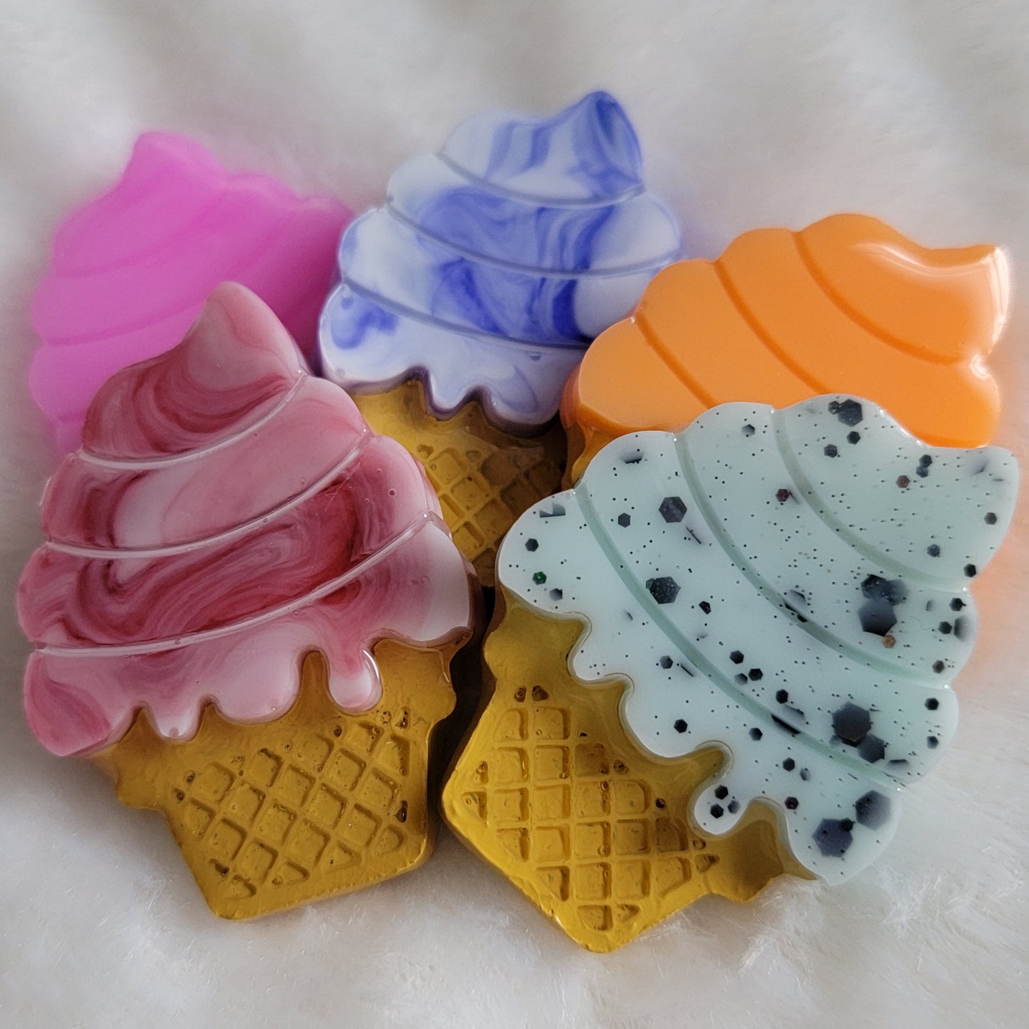 Five ice cream cone shaped epoxy resin pieces, colors shown are bright pink, blue and white swirl, deep red and white swirl, bright orange, and light green with black glitter.