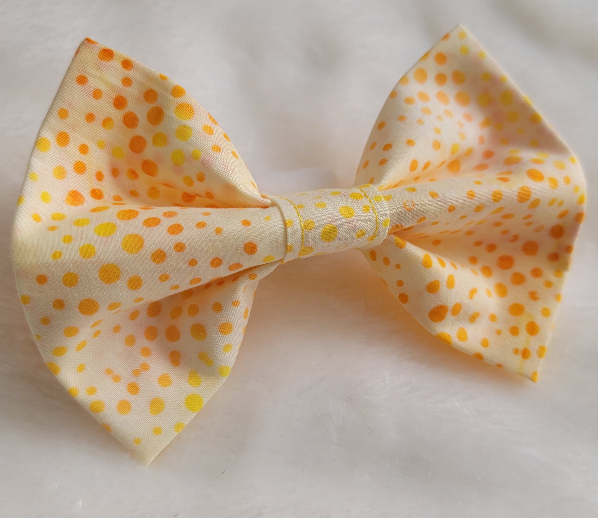 Bright orange and yellow dot batik pattern on white fabric bowtie.