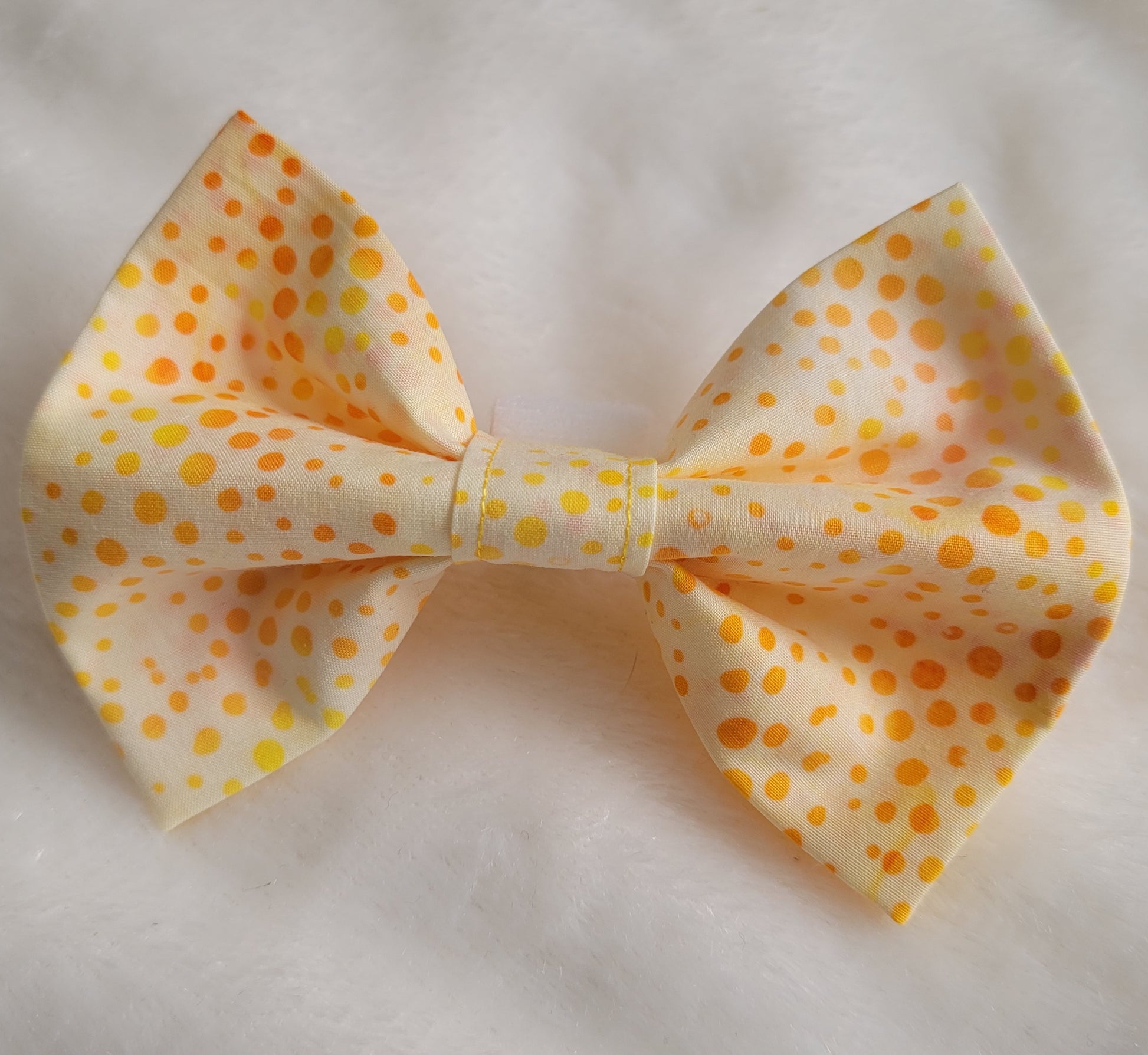 Bright orange and yellow dot batik pattern on white fabric bowtie.