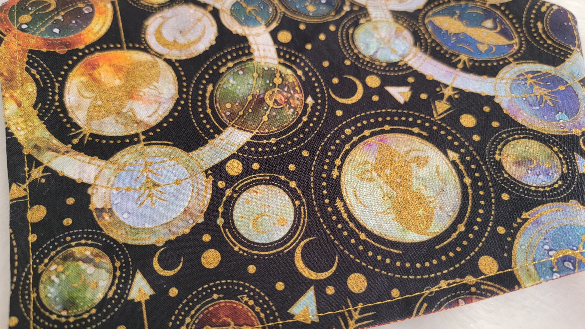 Reversible pet bandana, black and  multicolor cosmic moons and planets geometric design close up.