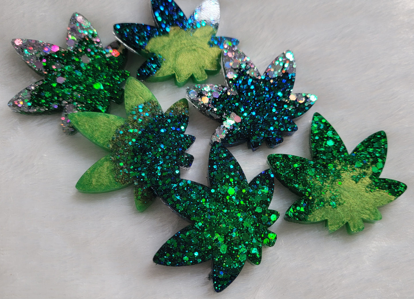 Six shimmering green and silver epoxy resin cannabis leaf shaped pieces.