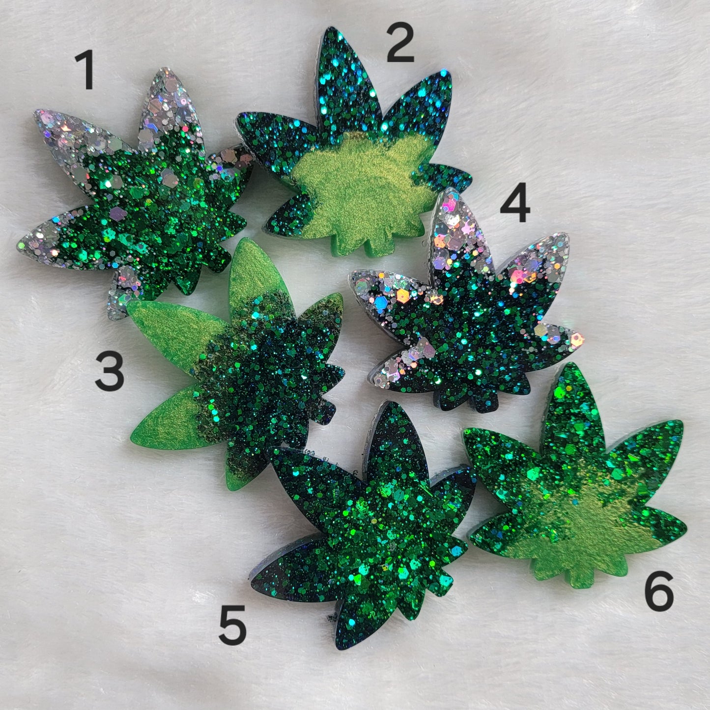 Six shimmering green and silver epoxy resin cannabis leaf shaped pieces.