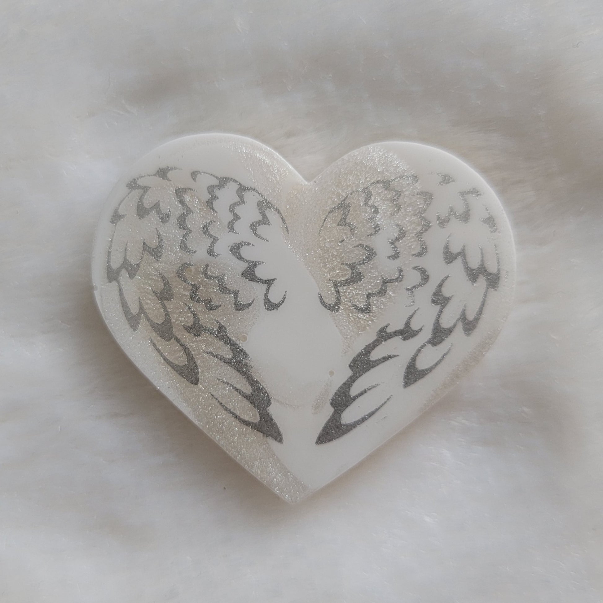 Heart shaped resin piece, white swirled base with silver sparkly angel wings design.