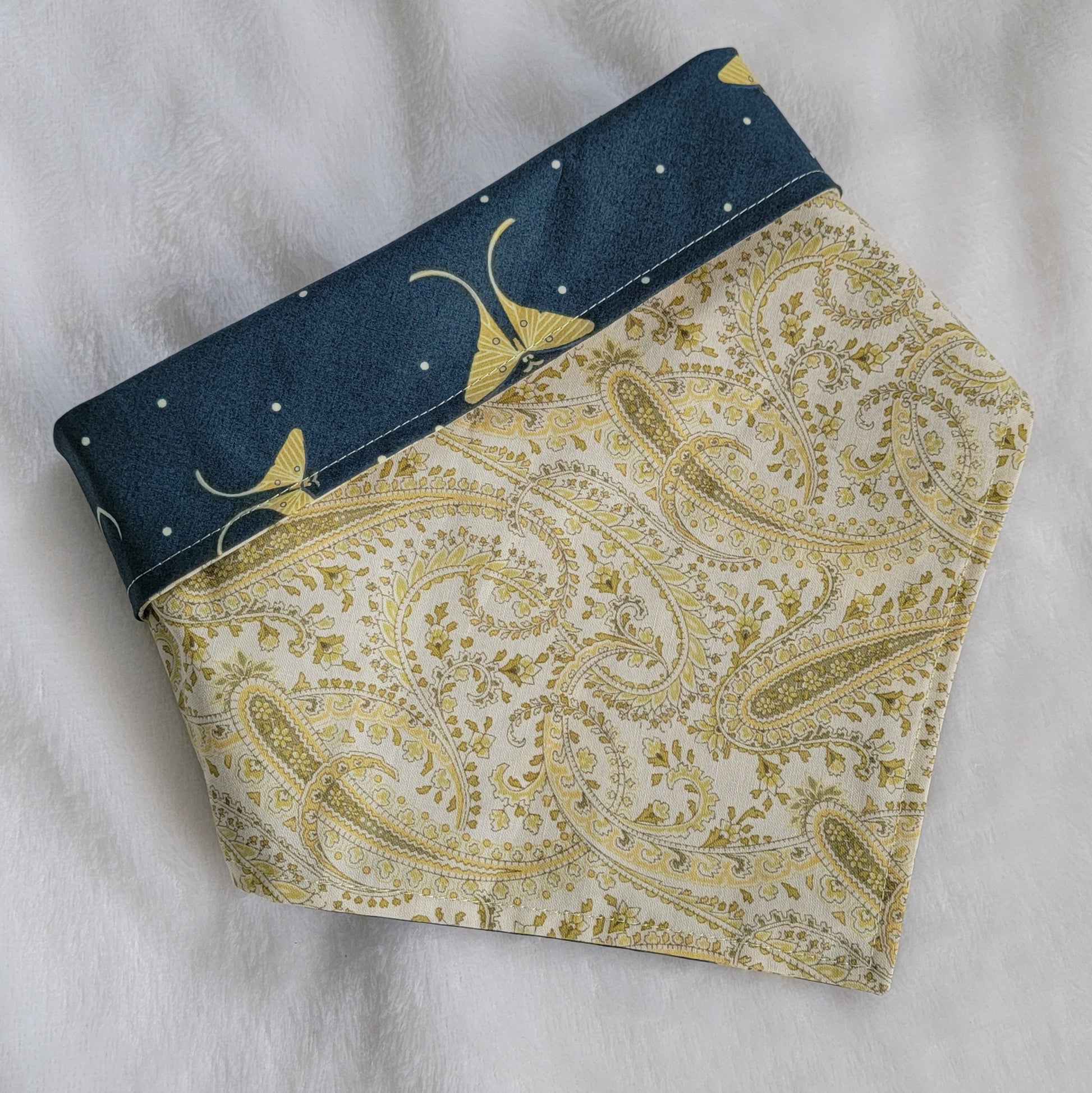 Reversible pet bandana, pale paisley print with top edge folded down to show reverse side in deep blue-green with moons and Luna moths print.