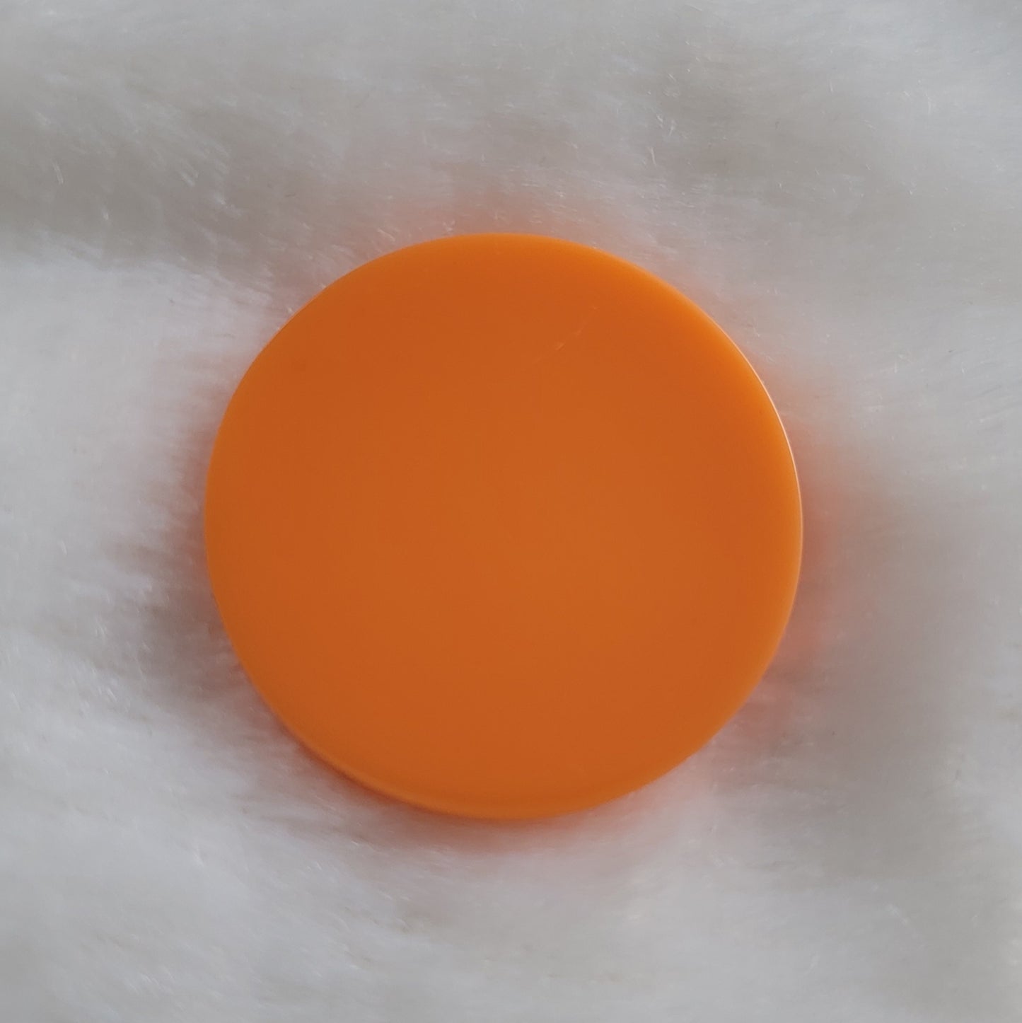 Solid Bright neon orange pigmented round epoxy resin piece.