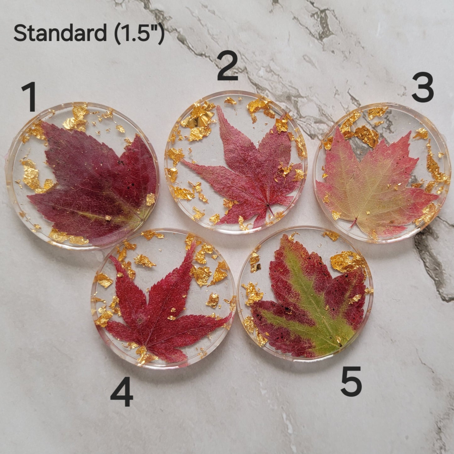 Five round epoxy resin pieces with deep red fall leaves and gold foil flakes cast in them, photo shows options for standard 1.5" size.