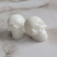 Two small bright white epoxy resin skulls.