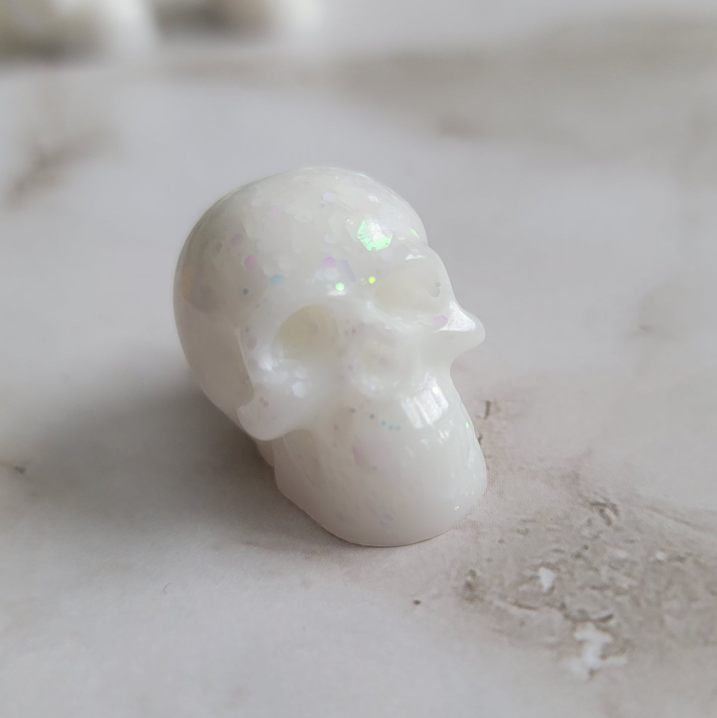 Small epoxy resin skull, bright white with iridescent white glitter.