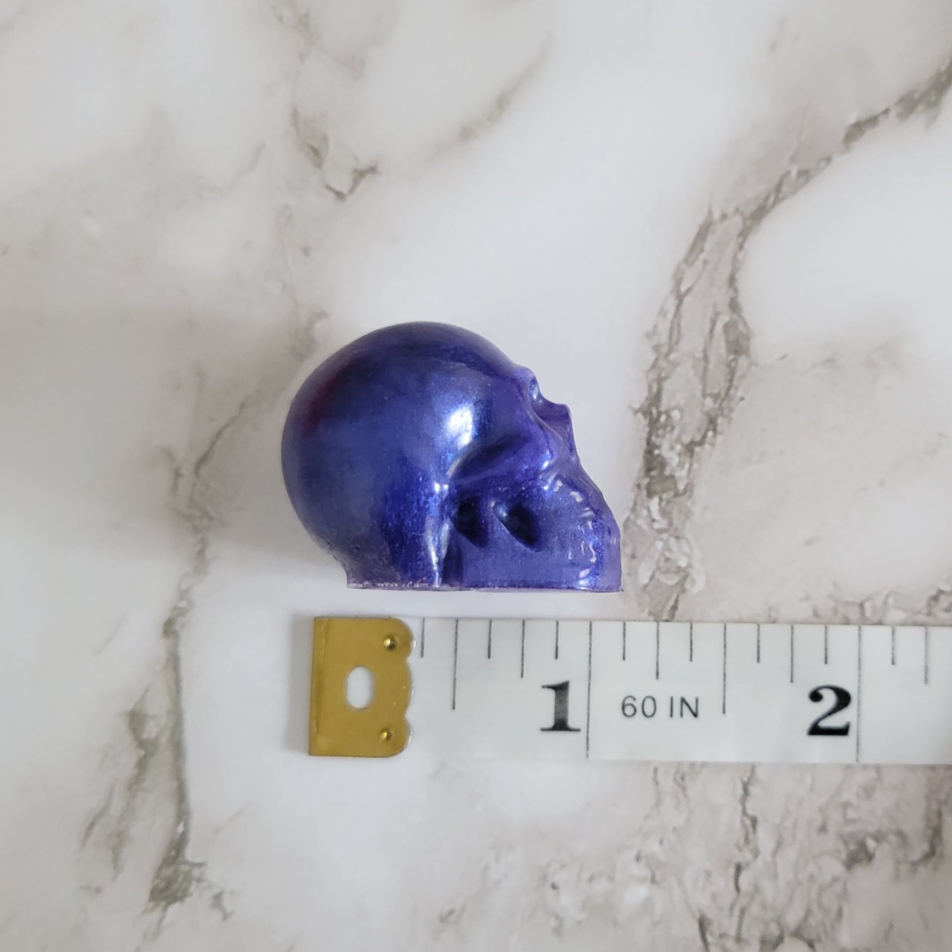 Small purple epoxy resin skull with measuring tape to show depth of piece measures 1.125".