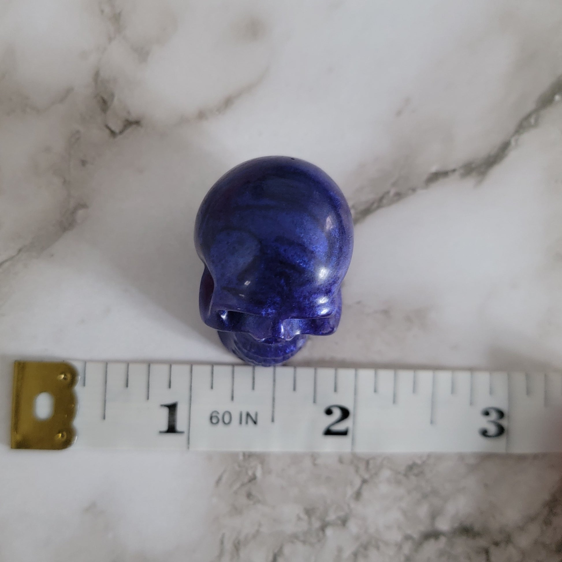 Small purple epoxy resin skull with measuring tape to show width of piece measures 0.88".