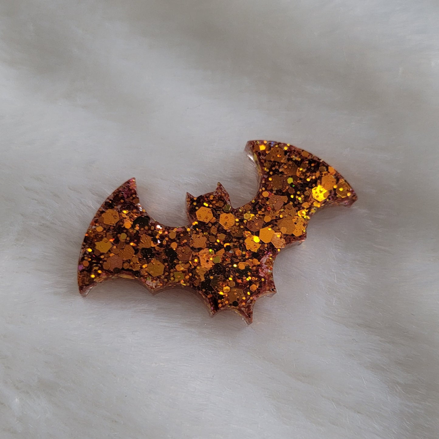 Orange glitter bat shaped epoxy resin piece.