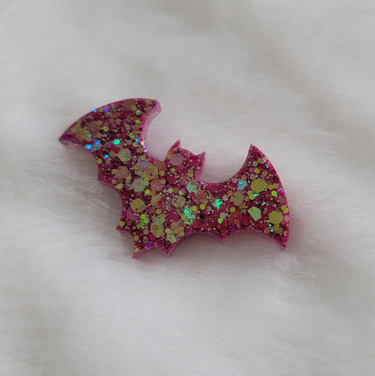 Pink-green chameleon glitter bat shaped epoxy resin piece.