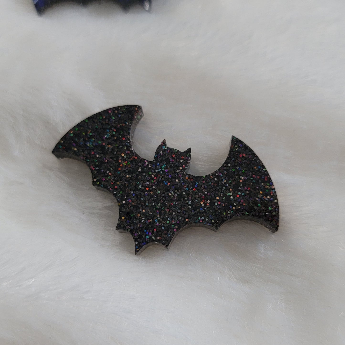 Fine black holographic glitter bat shaped epoxy resin piece.