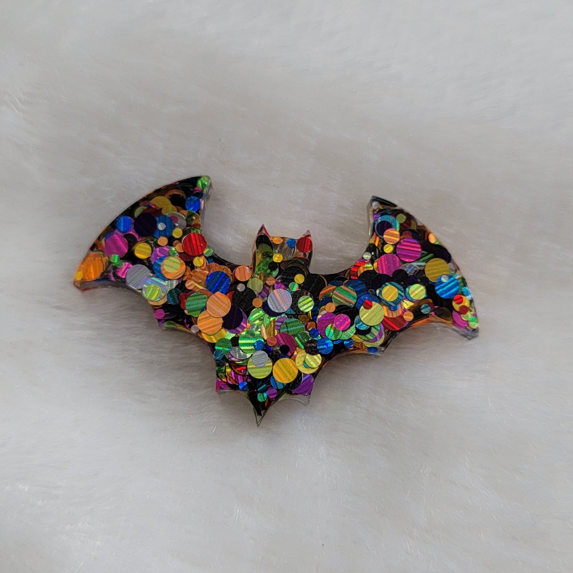 Multicolor dot glitter bat shaped epoxy resin piece.