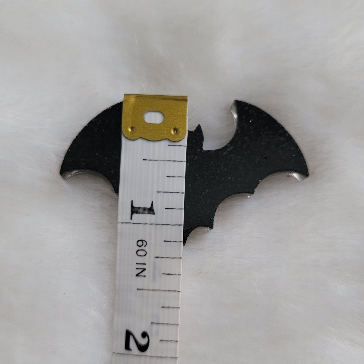 Small black glitter epoxy resin bat with measuring tape to show height of piece is 1.125".