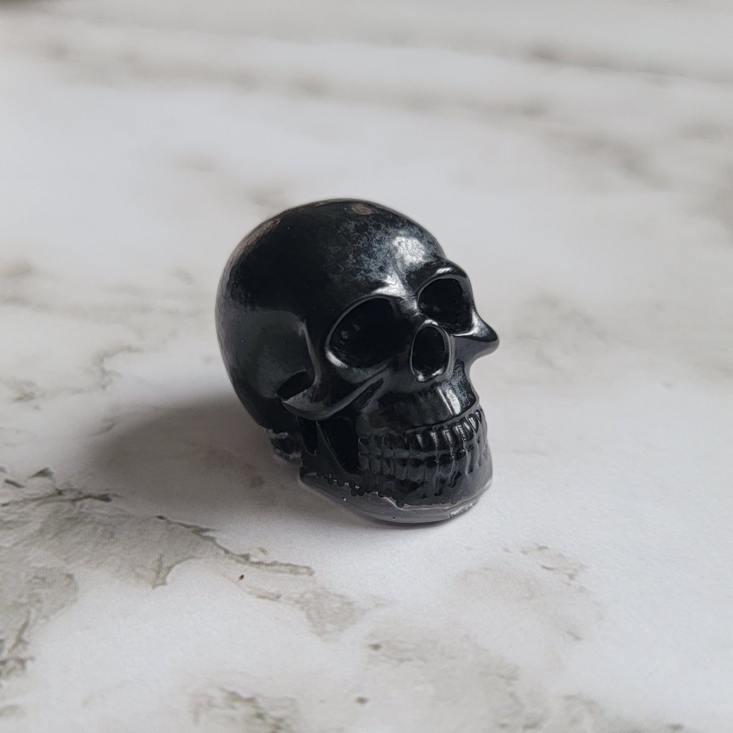 Small epoxy resin skull filled with black microbeads.