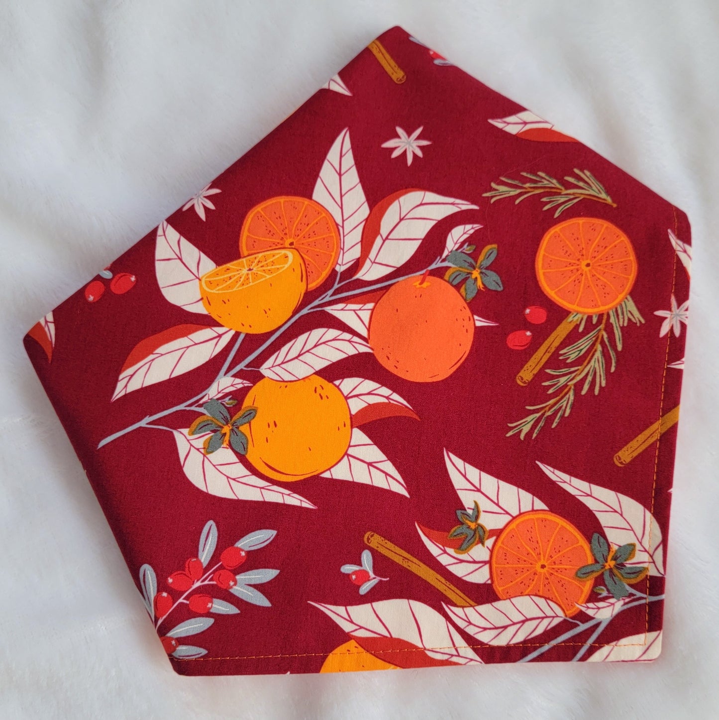 Handmade pet bandana, deep burgundy fabric with bright orange citrus and cinnamon and spices print.