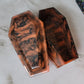 Coffin shaped epoxy resin trinket box with sparkly orange and black swirls.