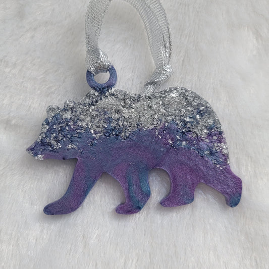 Bear shaped epoxy resin ornament, made with silver foil flakes with lavender and light blue swirls and a sparkling silver ribbon attached.