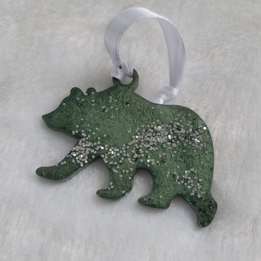 Bear shaped epoxy resin ornament, made with deep green mica pigment, bright silver glitter and a white ribbon attached.