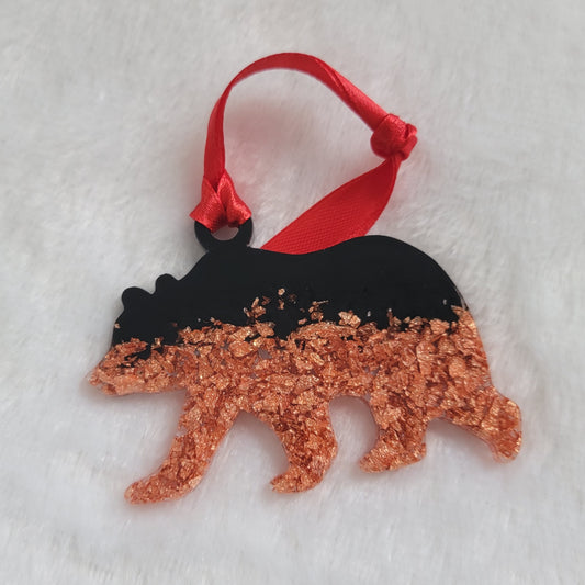 Bear shaped epoxy resin ornament, made with copper foil flakes and black pigment and a bright red ribbon attached.