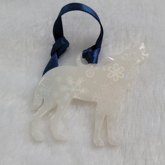 Wolf shaped epoxy resin ornament, made with white pigment with a holographic snowflake print vinyl covering the entire piece and a dark blue ribbon attached.