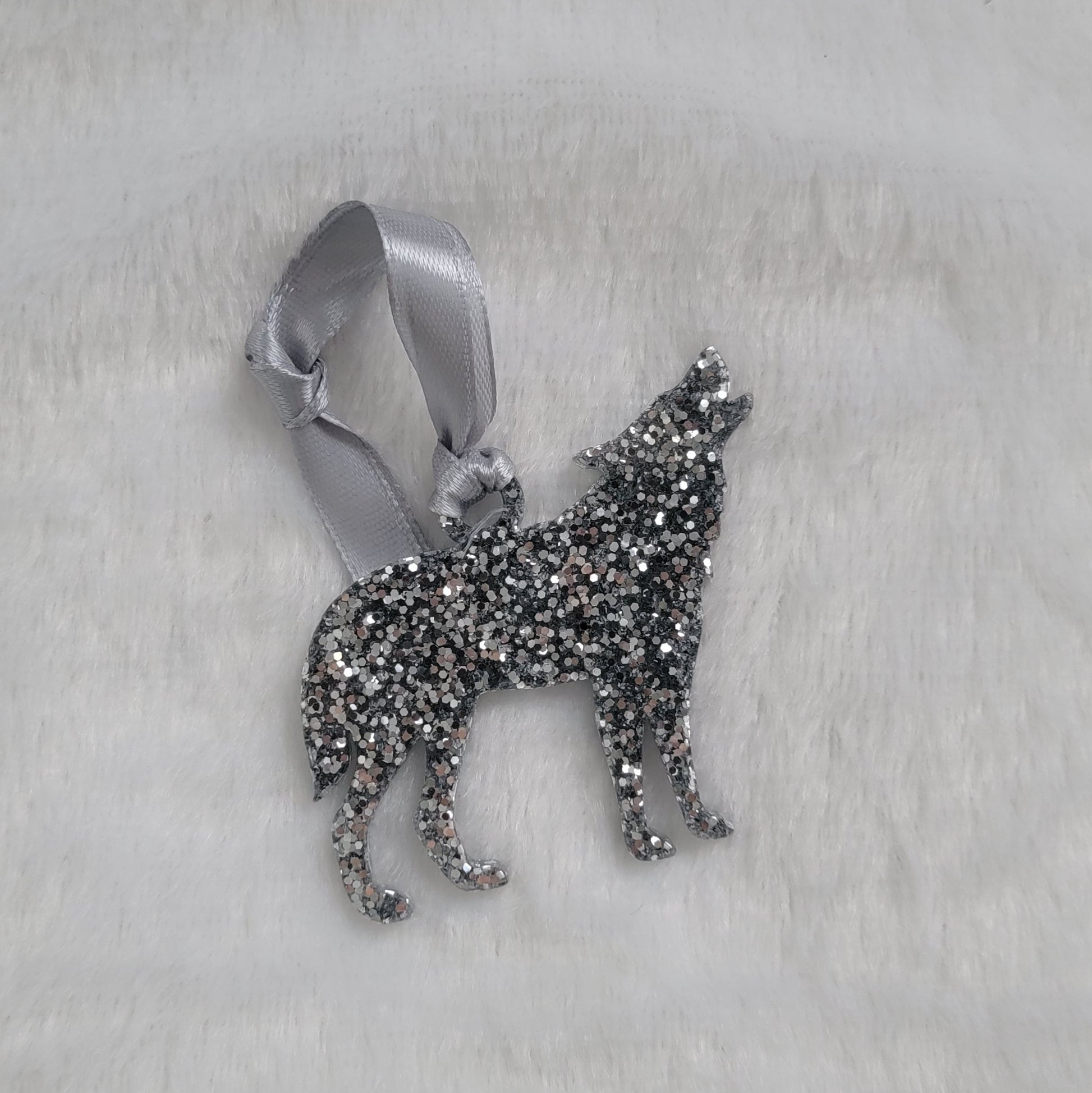 Wolf shaped epoxy resin ornament, made with bright silver glitter and a silver ribbon attached.