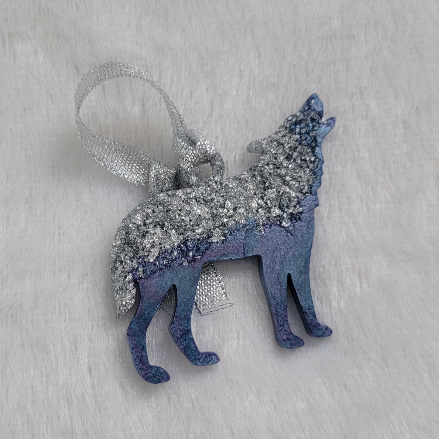 Wolf shaped epoxy resin ornament, made with silver foil flakes with lavender and light blue swirls and a sparkling silver ribbon attached.