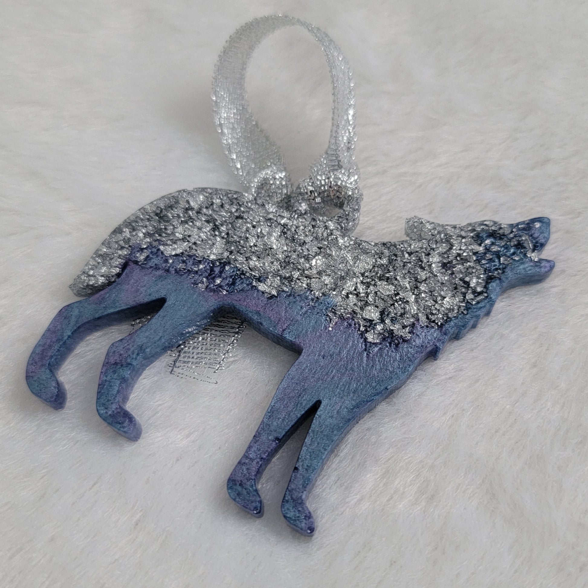 Wolf shaped epoxy resin ornament, made with silver foil flakes with lavender and light blue swirls and a sparkling silver ribbon attached.