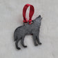 Wolf shaped epoxy resin ornament, made with dark silver pigment and a red ribbon attached.