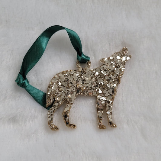 Wolf shaped epoxy resin ornament, made with warm silver glitter and a dark green ribbon attached.